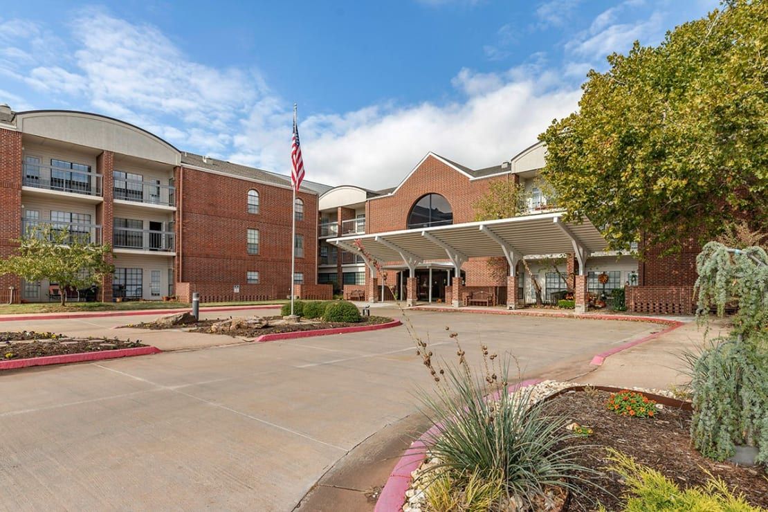 A residential building with a prominent entrance and landscaped driveway under a clear sky.