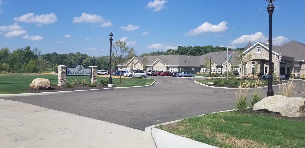 A peaceful suburban residential area with single-story buildings and a parking lot filled with cars under a bright blue sky.
