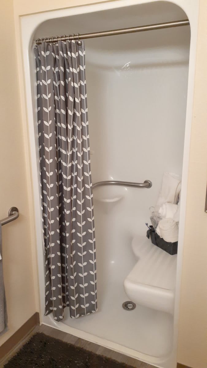 A bathroom with a shower featuring a patterned curtain and neatly folded towels.