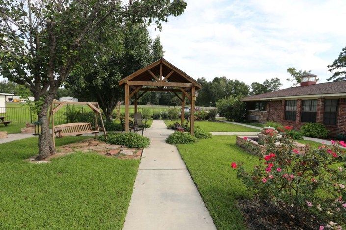 A peaceful garden with a wooden gazebo and well-maintained pathway.