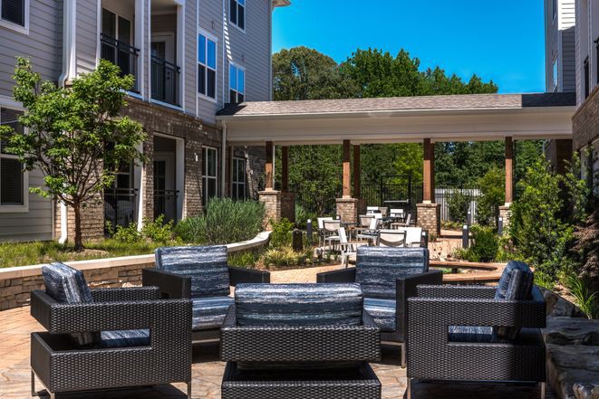 A modern outdoor seating area with rattan chairs in an apartment complex.