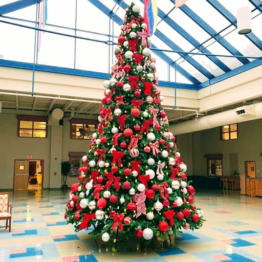 A beautifully decorated Christmas tree adorned with red and white ornaments, standing tall in a spacious indoor area.