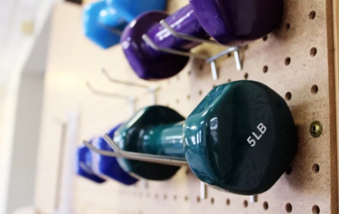 Colorful dumbbells neatly arranged on a rack in a gym.