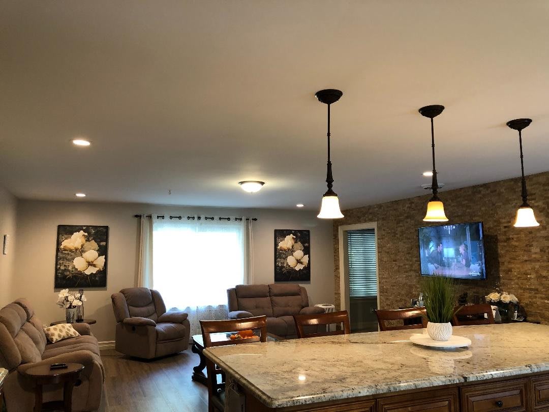 A cozy open-plan living area with a kitchen island, complete with pendant lights, comfortable seating, and a TV.