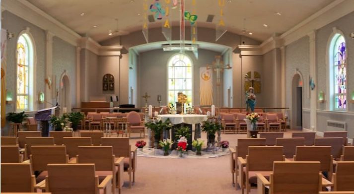 A beautifully decorated church interior featuring an altar surrounded by seating and floral arrangements.