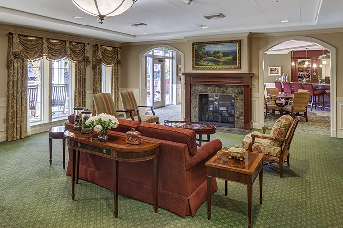 A cozy living room with elegant furniture, featuring a fireplace and artwork.