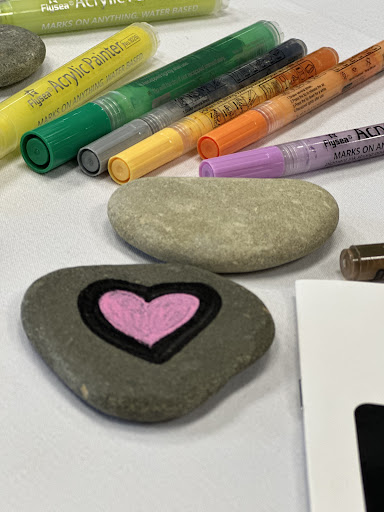 Creative stones adorned with a heart design, surrounded by vibrant art supplies.