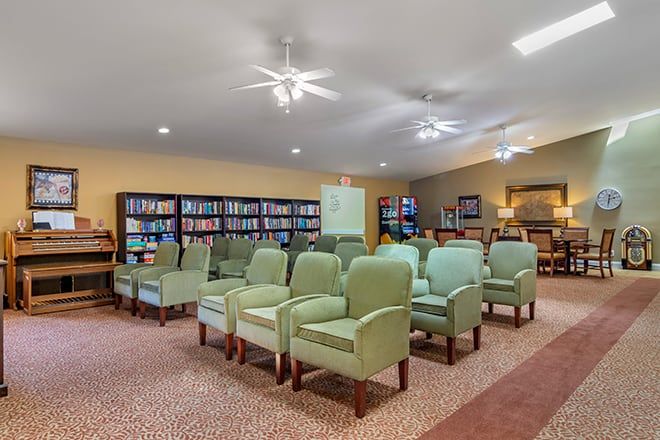 A cozy library with a row of green chairs and well-stocked bookshelves.