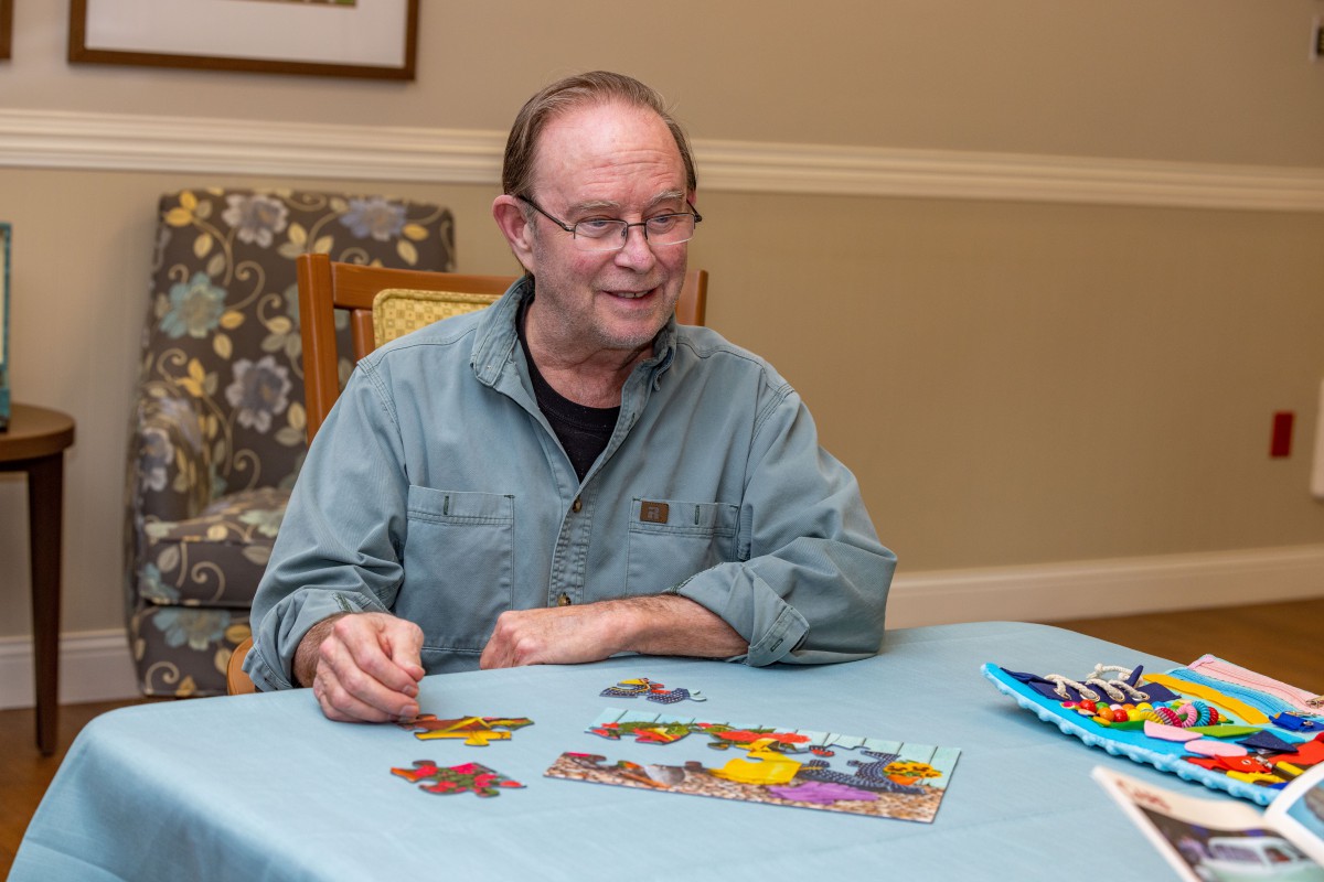 A man is enjoying a puzzle activity indoors at a table.
