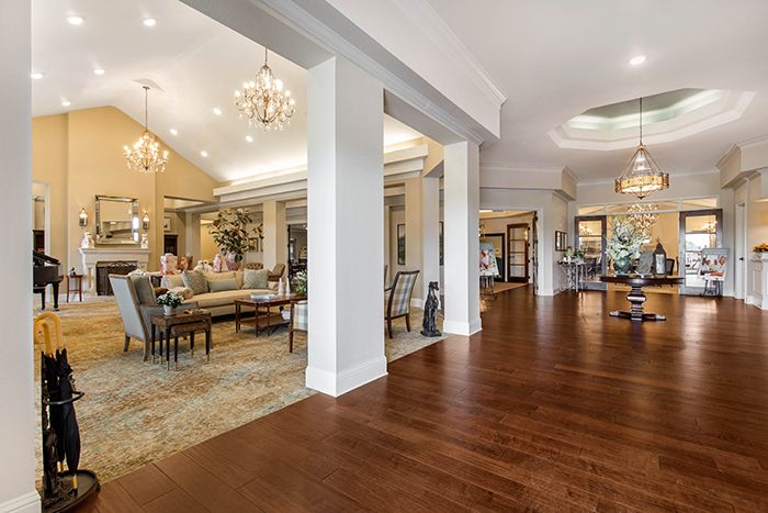 A luxurious open living room with hardwood floors and elegant chandeliers.
