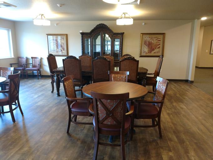 A dining room with wooden furniture, featuring a round table surrounded by chairs and a large cabinet in the background.