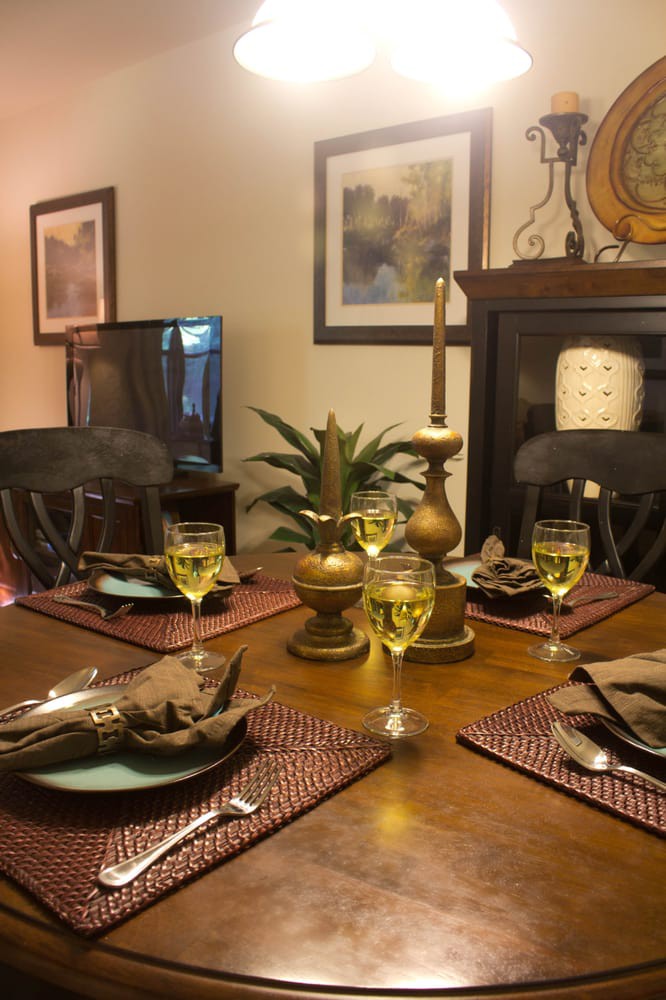 A warmly lit dining table set for a meal, featuring elegant candles and a decorative centerpiece.