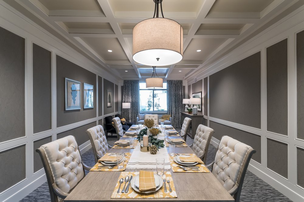 A modern and elegant dining room with a well-set table and upholstered chairs under stylish chandeliers.