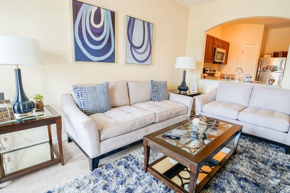 A well-decorated living room featuring a modern sofa set, a glass coffee table, and abstract artwork on the walls.