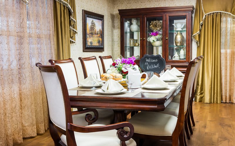 An elegantly set dining table with a floral centerpiece and neatly arranged table settings.