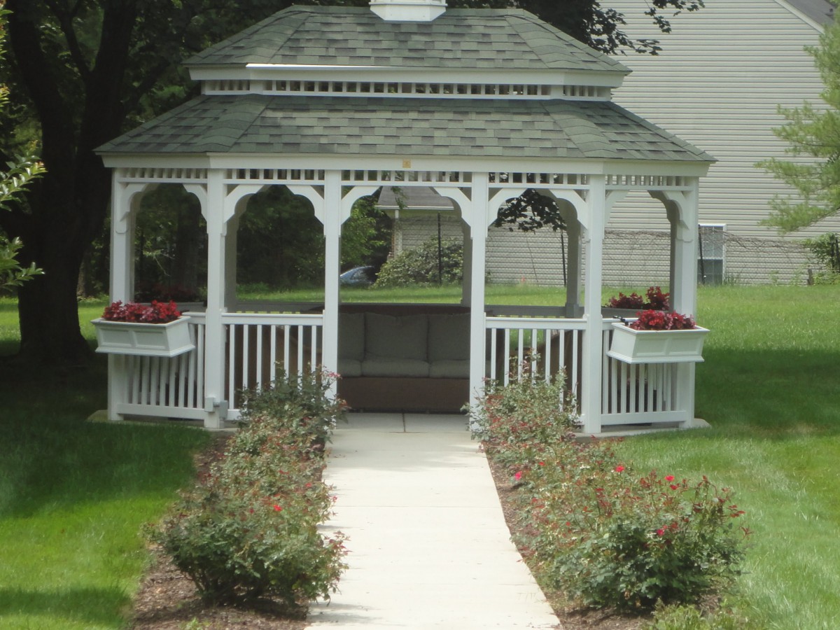 A charming white gazebo surrounded by a garden path with flower beds.