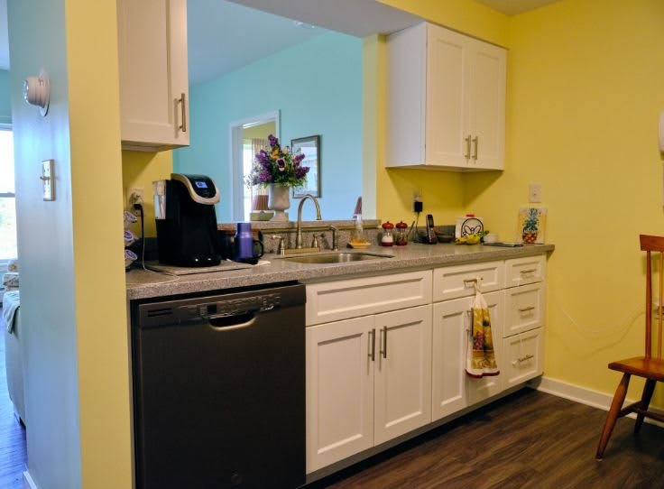A well-organized kitchen with yellow walls, white cabinets, and a modern design.