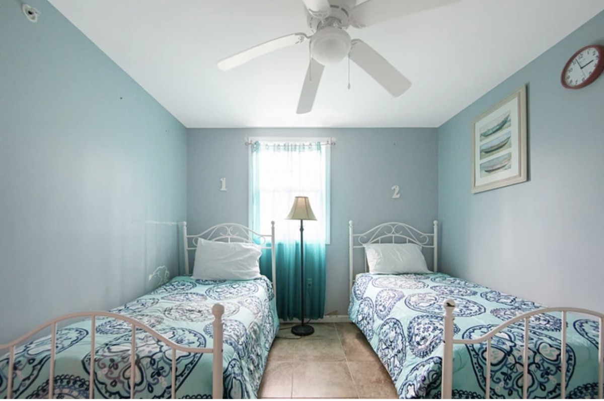 A cozy bedroom with twin beds, blue walls, and a ceiling fan.