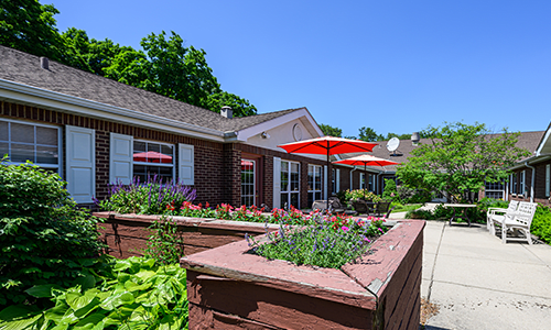 A charming outdoor patio area with red umbrellas and a well-maintained garden.
