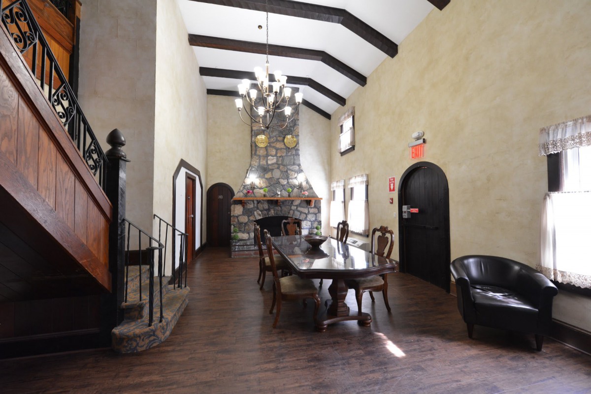 A spacious dining room with a long table, high ceiling, and a grand chandelier.
