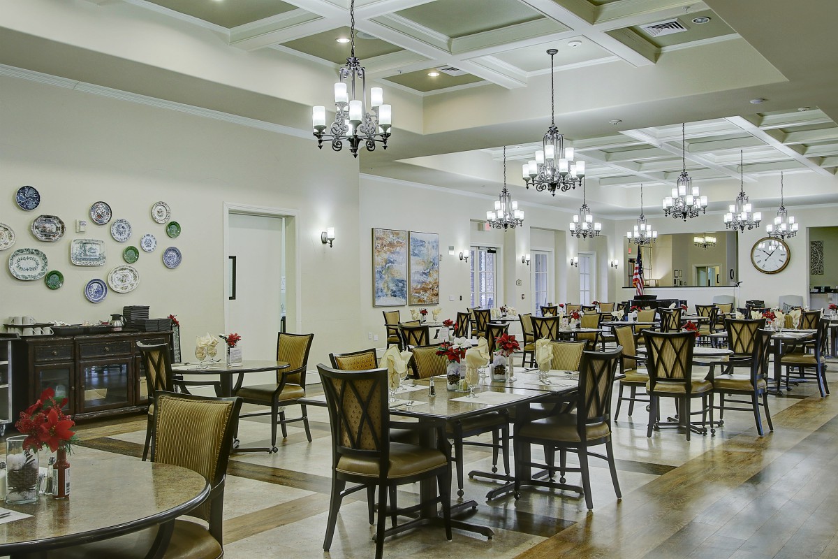 A spacious dining room with elegant chandeliers and neatly arranged tables and chairs.