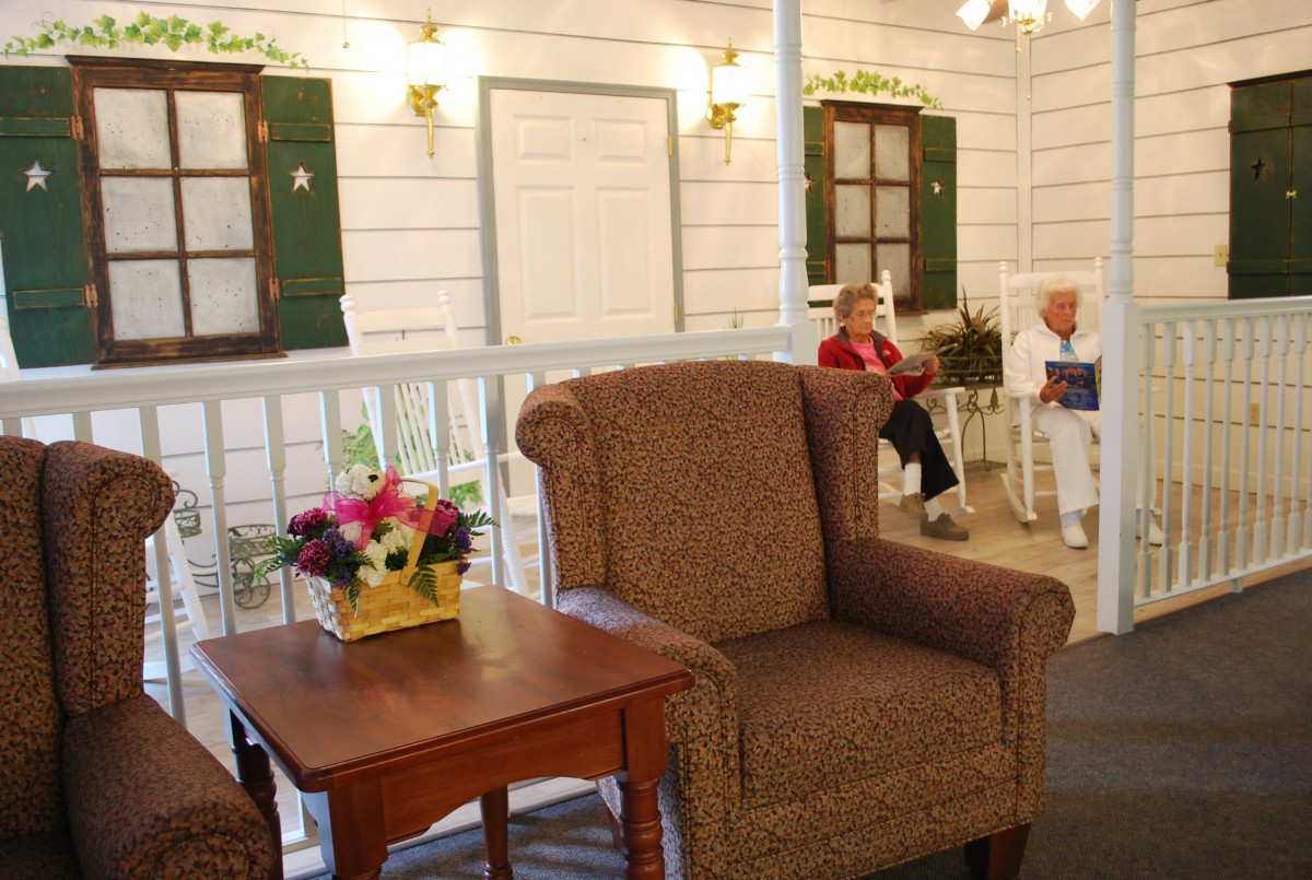 A cozy seating area with an armchair, table, and flowers, with people in the background.