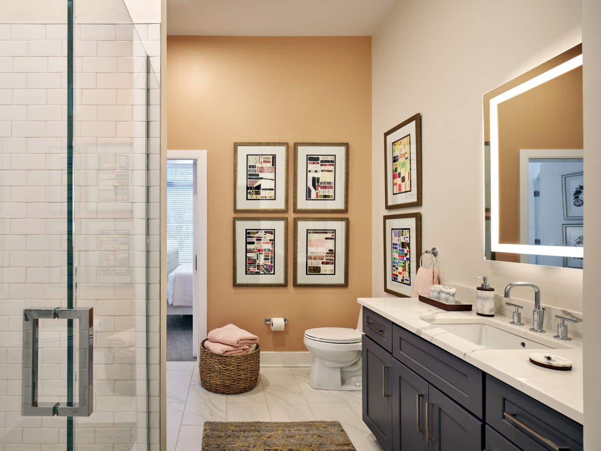 A modern bathroom with a double vanity, framed art on the wall, and a glass-enclosed shower.