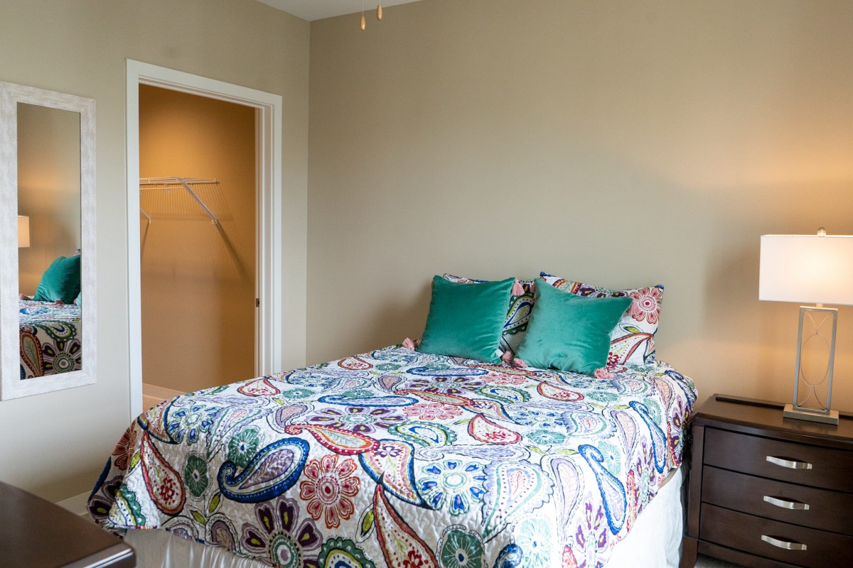 A cozy bedroom with colorful bedding and teal pillows.
