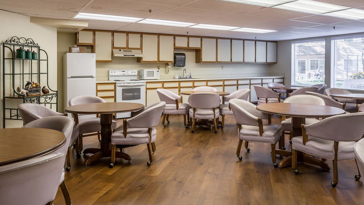 A spacious kitchen and dining area with wooden floors, featuring tables, chairs, cabinets, and standard kitchen appliances.