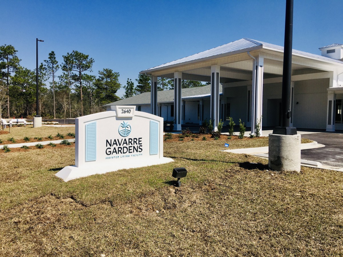 A modern building with a sign reading 'Nuggets Gardens' set against a clear blue sky.