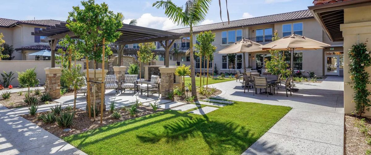 A beautifully landscaped outdoor patio area featuring comfortable seating, lush greenery, and palm trees.