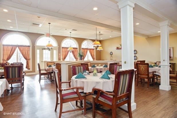 A well-lit dining area with neatly arranged tables and chairs, featuring elegant decor.
