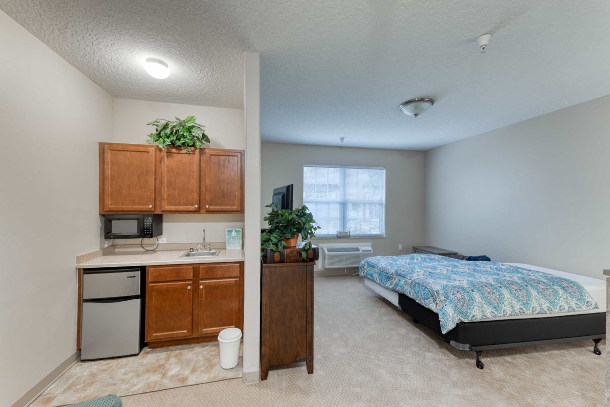 A cozy studio apartment featuring a compact kitchen area and a bedroom space.
