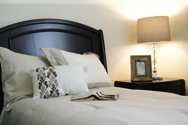 A cozy bedroom with a neatly made bed and a lit lamp on the nightstand.