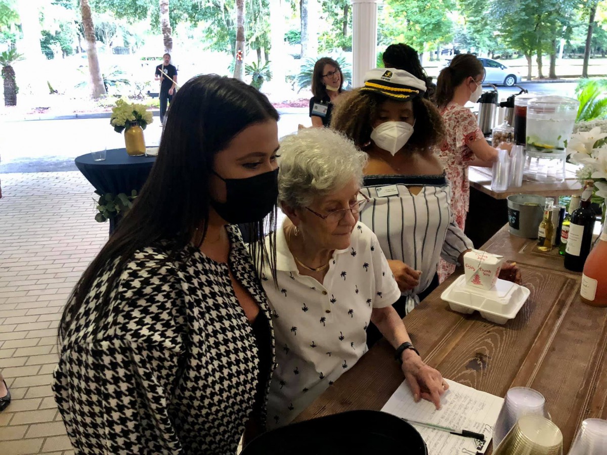 A group of people at a social event, with two individuals posing for a photo during a book signing.