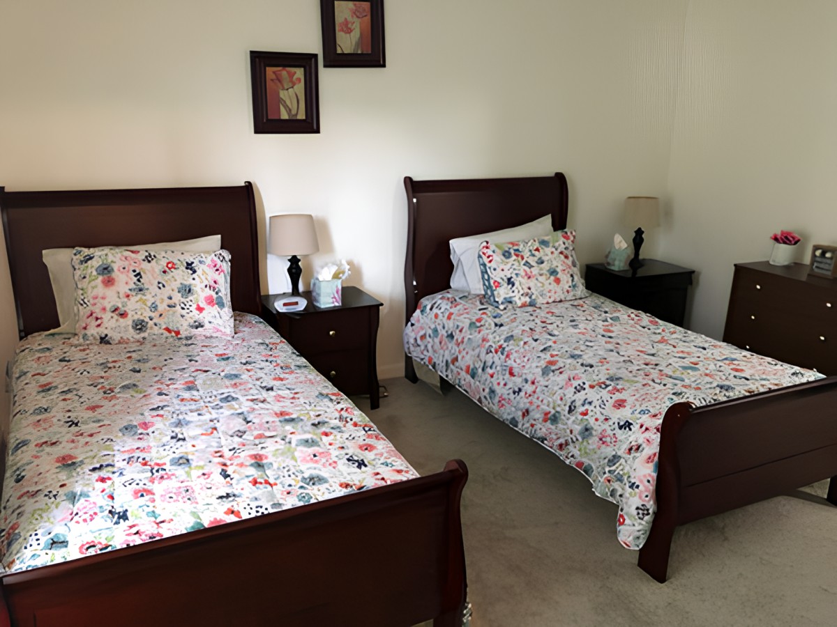 A cozy bedroom featuring two twin beds with floral bedding and matching nightstands.