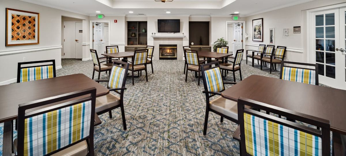 A cozy dining area with multiple tables and chairs, featuring a fireplace and television.