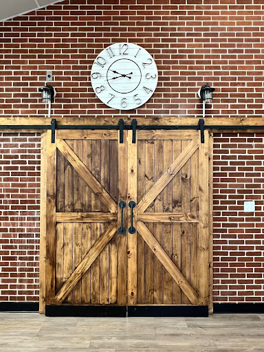 A rustic wooden barn door set against a brick wall, complemented by a vintage clock above.