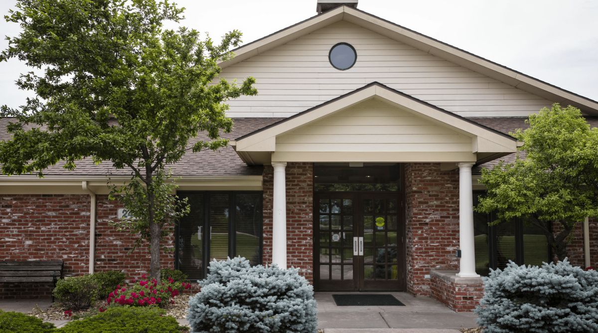 A residential building entrance with a brick exterior and landscaped surroundings.