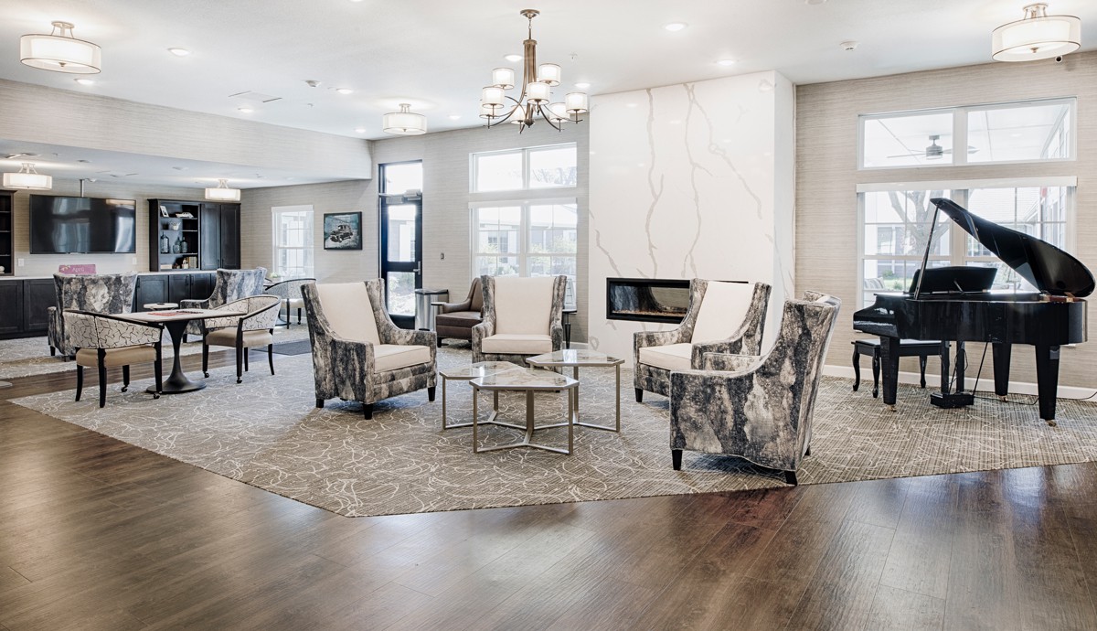 A modern living room with stylish chairs, a central table, and a sleek fireplace under bright lighting.