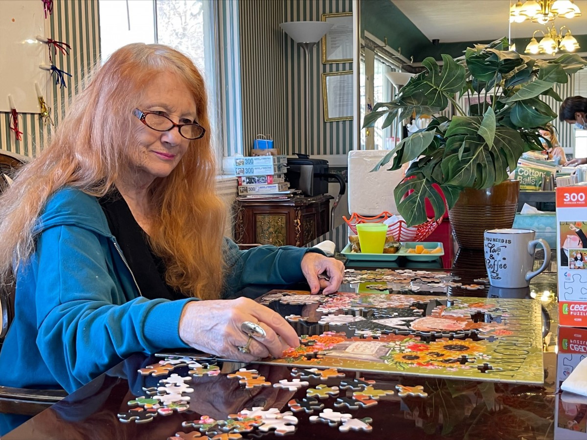 A woman enjoying assembling a jigsaw puzzle indoors.