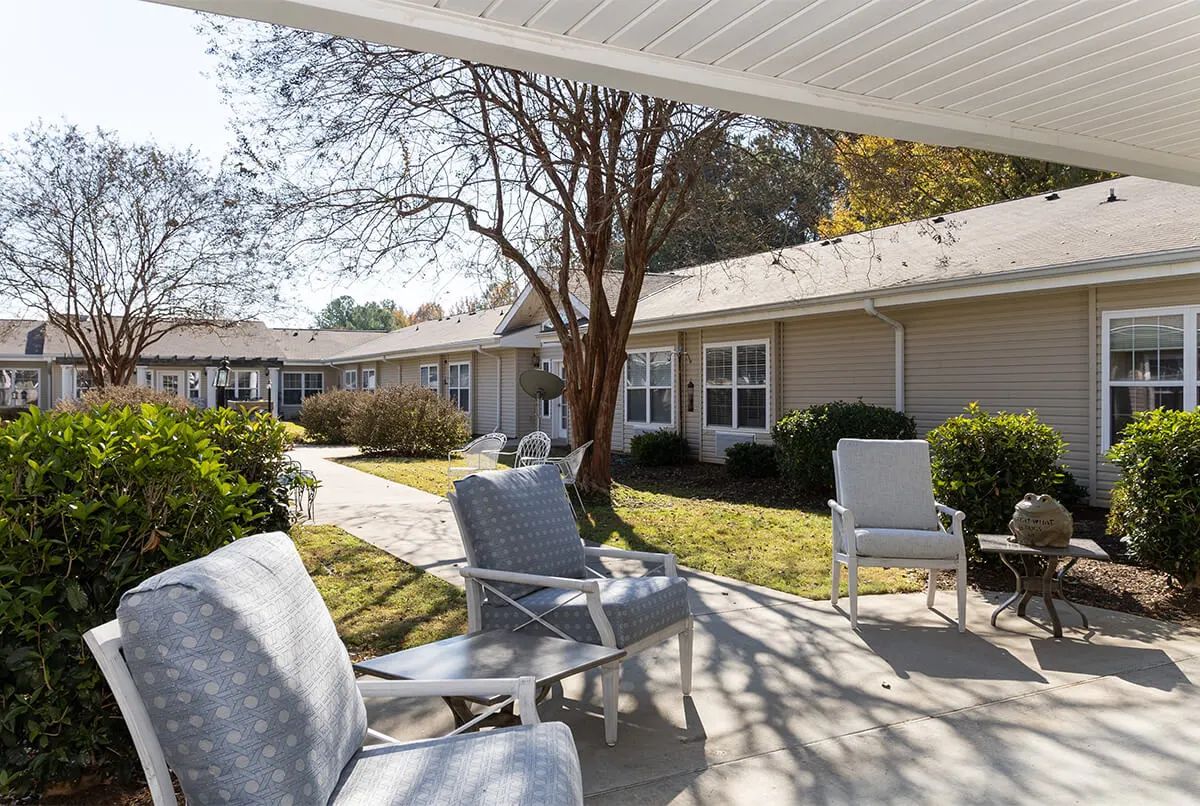 A peaceful courtyard with outdoor seating and a well-maintained garden on a sunny day.