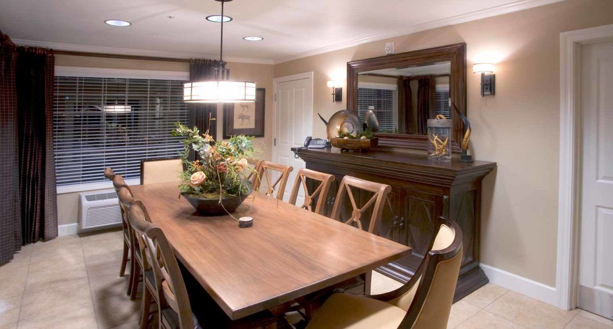 A well-decorated dining room featuring a large wooden table, elegant chairs, and stylish lighting.