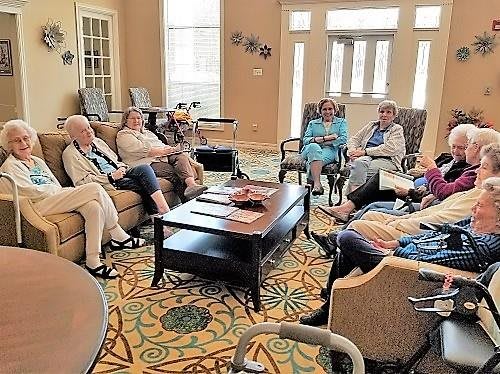 A group of seniors sitting in a living room having a discussion.