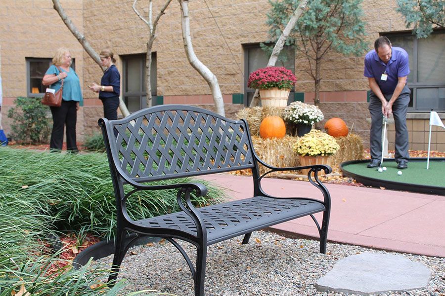 A decorative outdoor area with a bench, surrounded by pumpkins and colorful flowers.