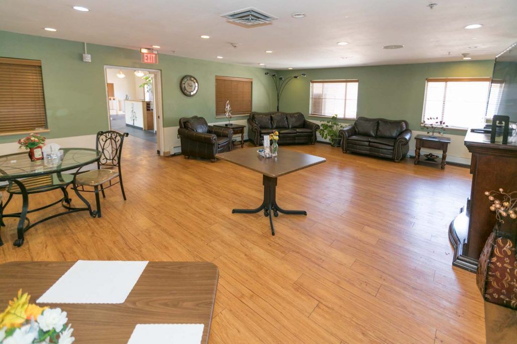 A spacious living room with sofas, chairs, tables, and hardwood flooring.