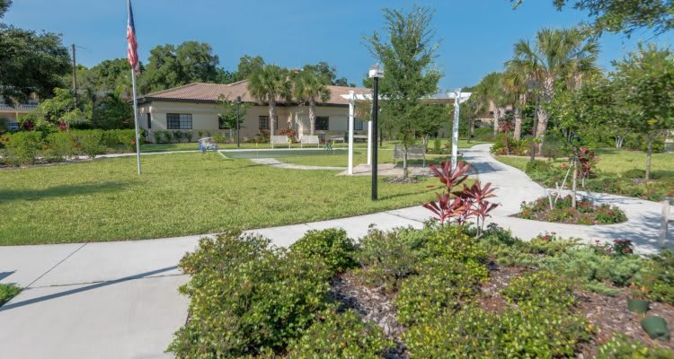 A serene garden with a winding pathway and a building in the background.