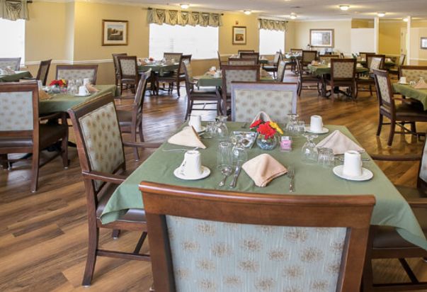 A neatly arranged dining room with tables set for a meal, featuring floral centerpieces and elegant decor.