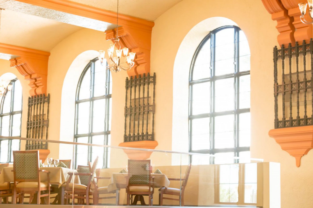 Bright and airy restaurant interior with large arched windows and elegant furniture.