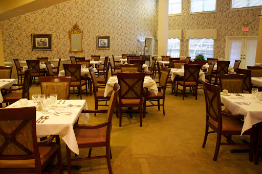A spacious and elegantly arranged dining area, featuring neatly set tables and comfortable chairs.
